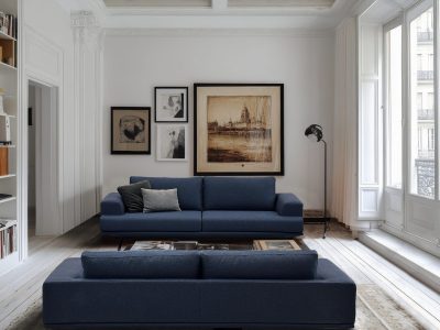 The spacious living room features large windows that let in natural light. Cozy seating arrangements include a leather couch and stylish chairs.