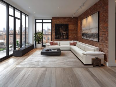 A stylish living area featuring a large orange sofa, wooden accents, and ample natural light. The open layout connects with a modern kitchen and dining area, creating a warm atmosphere.